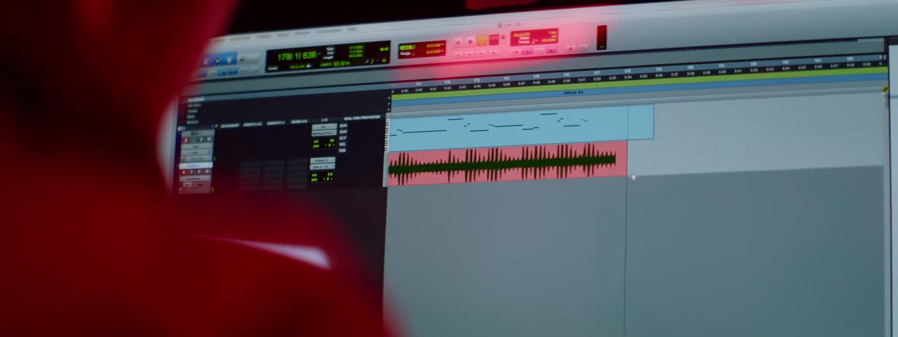A person uses audio editing software on a computer