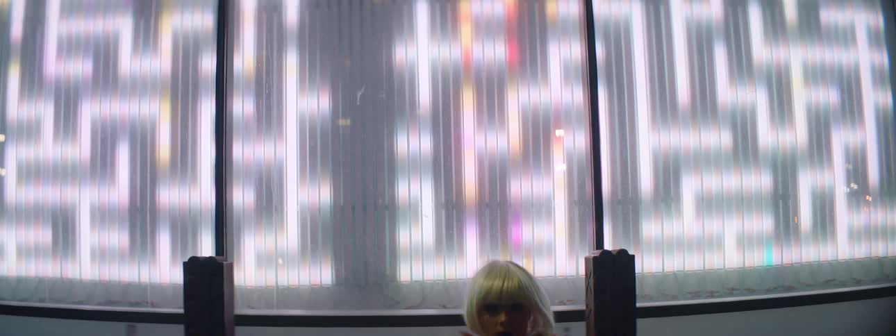 A teenage girl dances outside at night as lights flash behind her and cars drive past