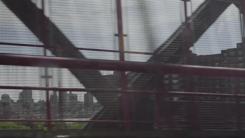 Moving over a bridge a city can be seen through the fence
