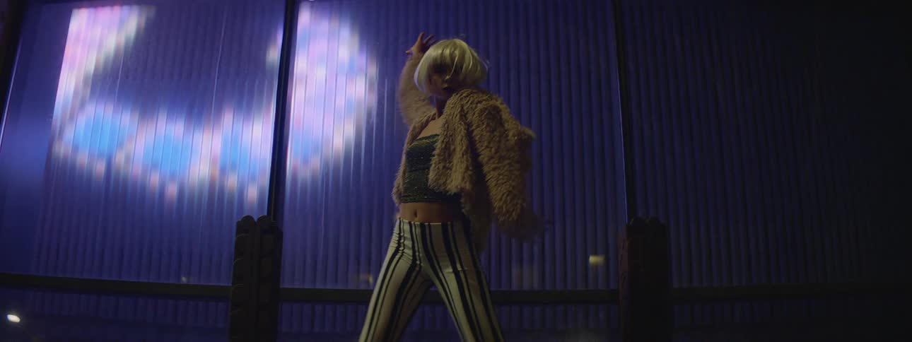 A female girl dancing outside with bright lights behind her