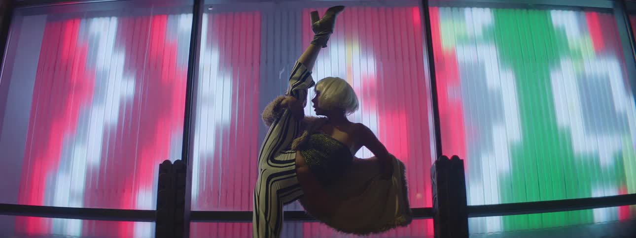 A young woman dances outside in front of bright lights