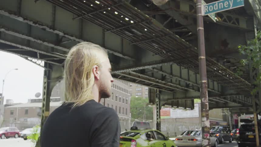 A man walks under train station on a sunny day