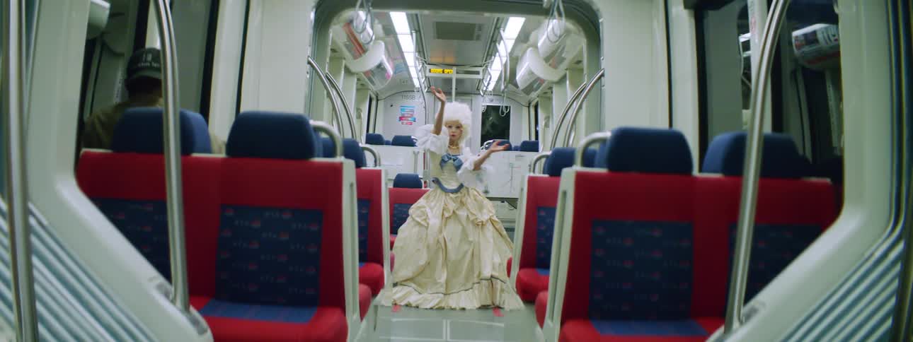 A woman with a dress and a wig standing on a train posing
