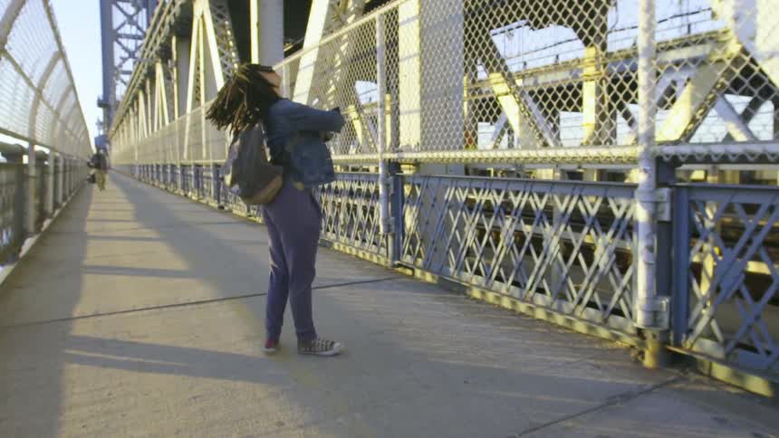 A woman is dancing as she walks across a bridge