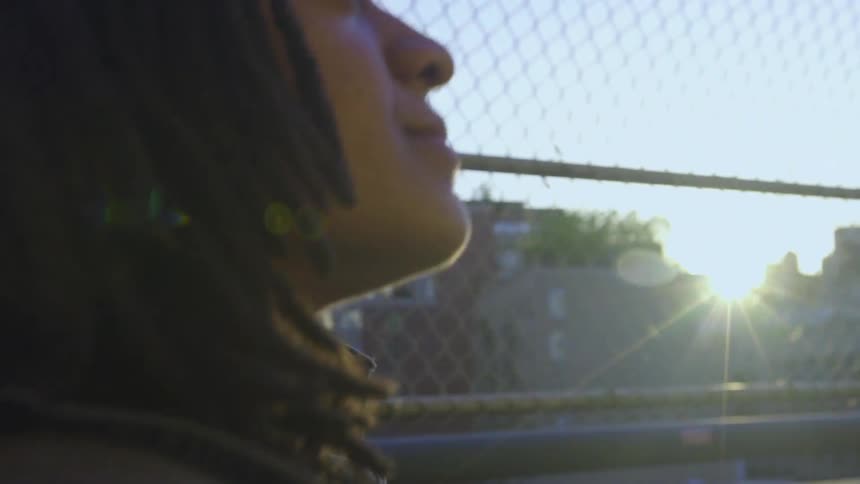 A woman walks on a bridge by a fence