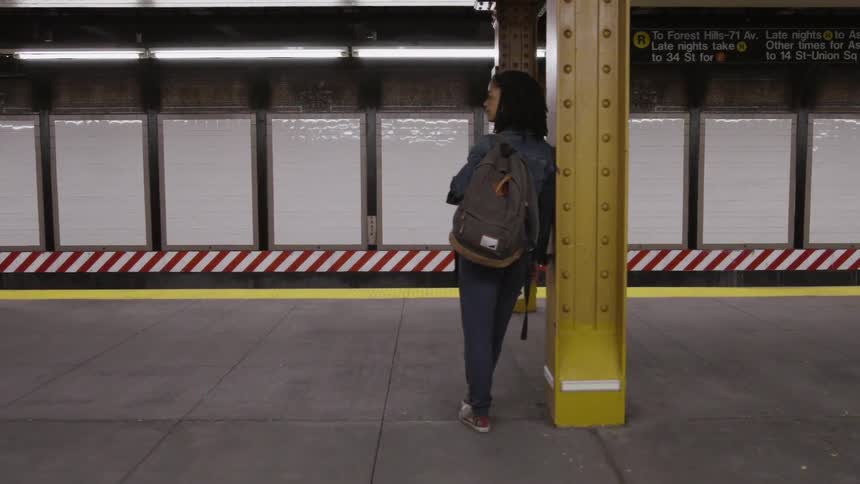 A woman leans against a yellow pillar