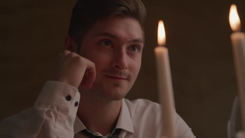 A man with a shirt and tie with candles and fire in the foreground