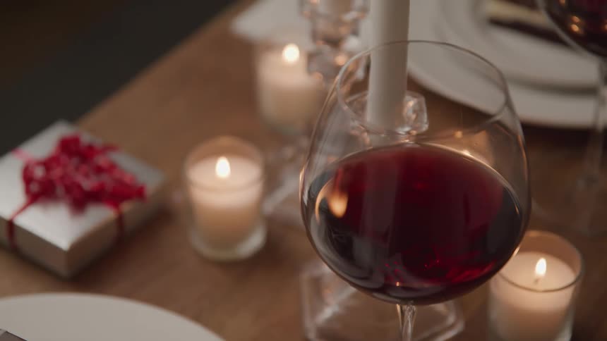 Glasses of wine on a table with candles and a gift