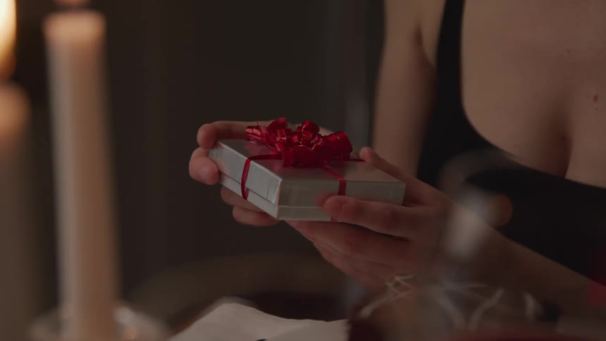 A woman sitting at a dining table picks up a gift