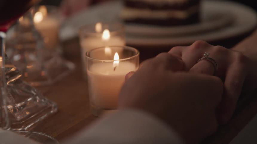 A couple hold hands at dinner
