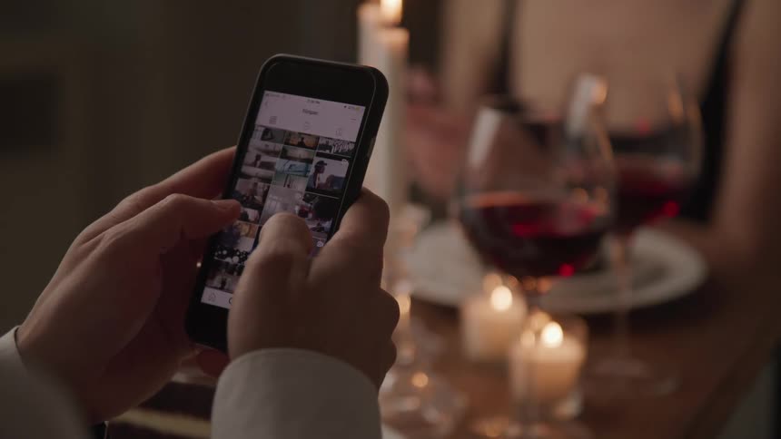 A person is using a cell phone at dinner