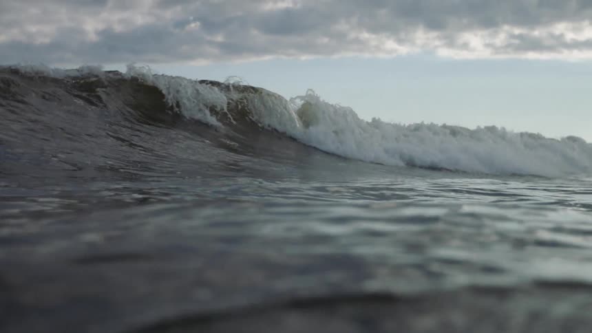 Waves curl under a cloudy sky