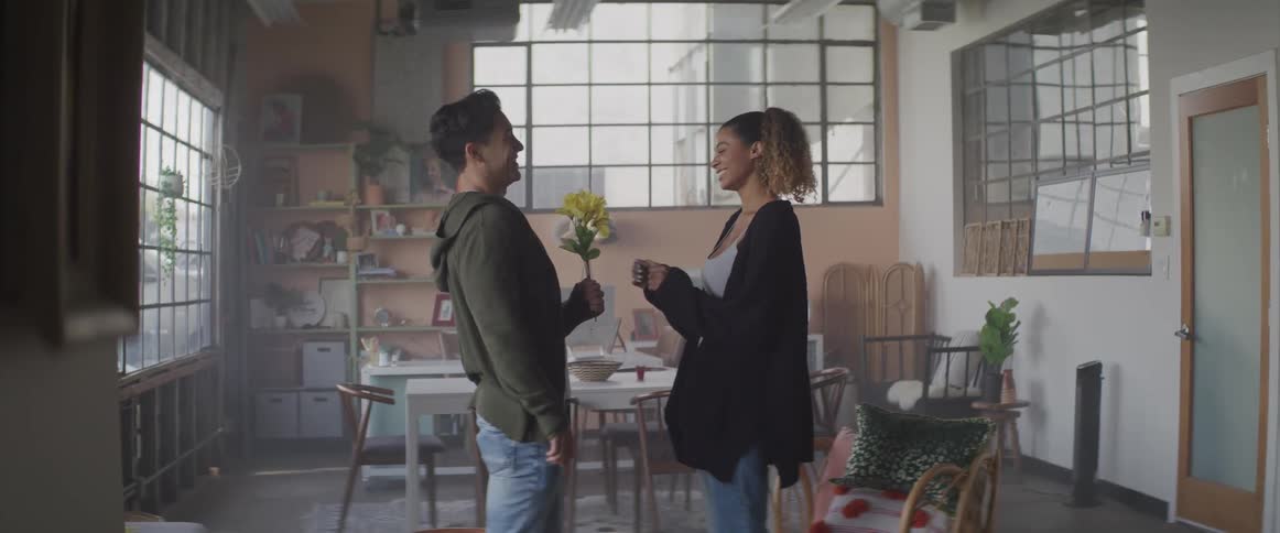 Young man surprises his girlfriend with yellow flowers receiving a hug back at home