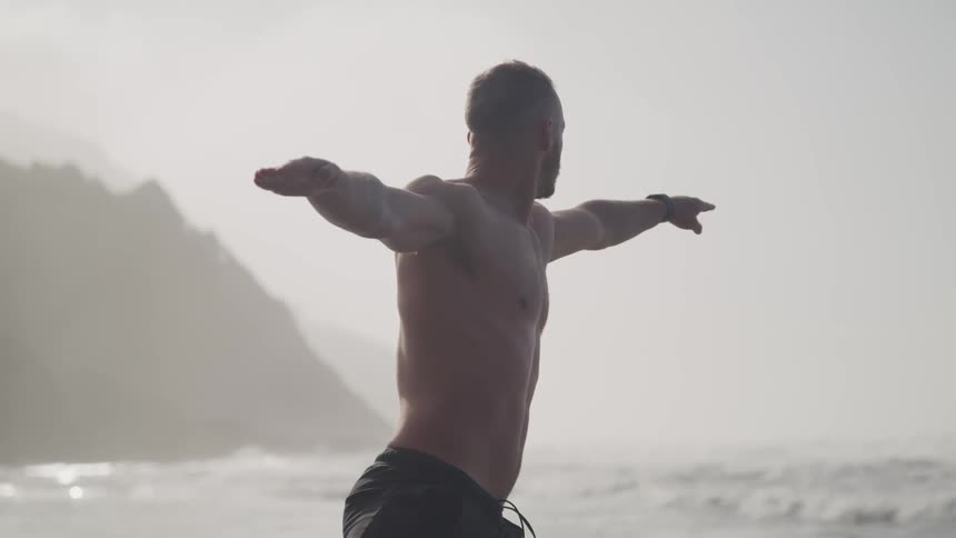 A man practices yoga on the shore