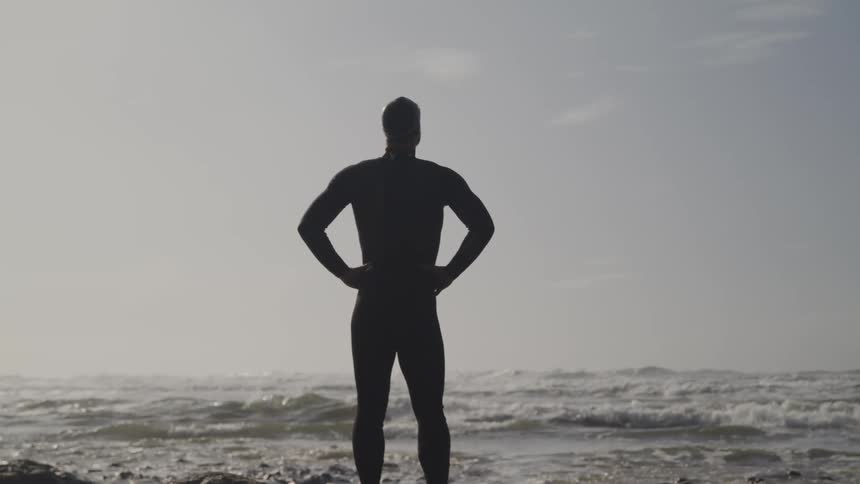 A man is standing by the coast of an ocean