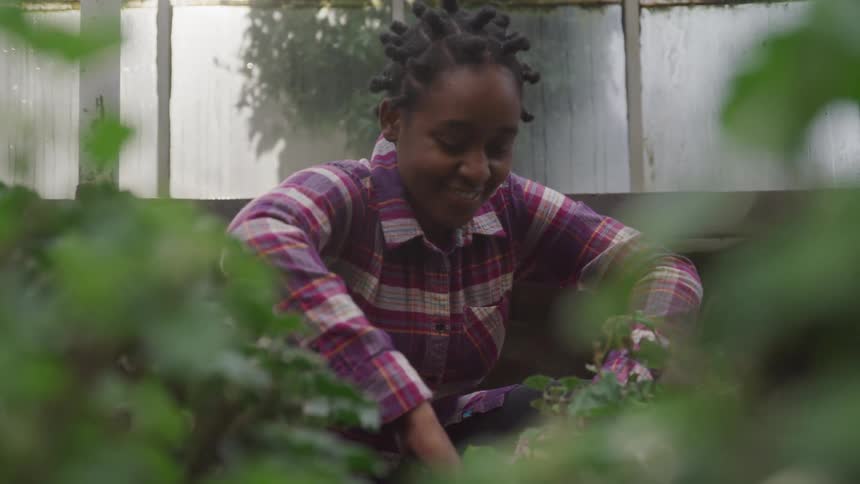 Teenage girl sitting in a garden smiles while planting