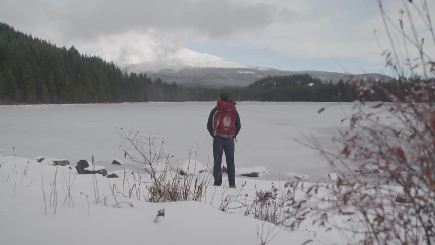 A man is outdoors in a forest area during winter