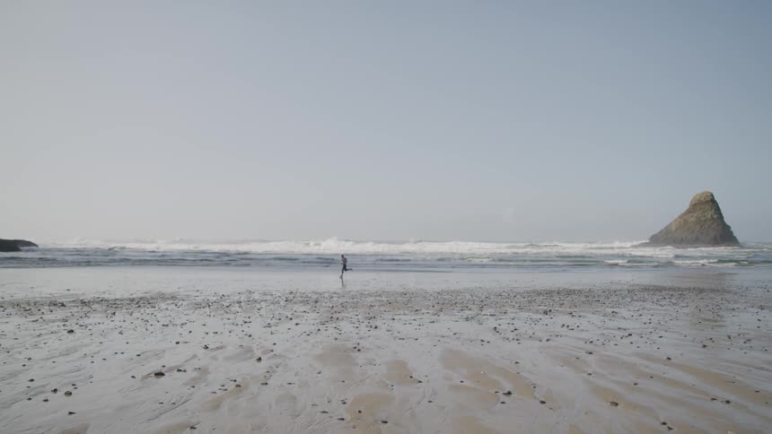A person running on a sandy beach next to the ocean