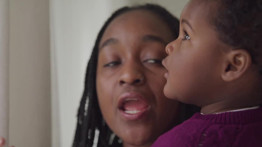 A mother is holding her daughter indoors