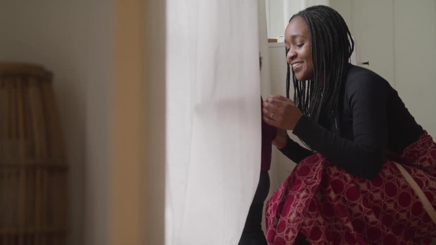 A woman stands next to a doorway with her toddler son looking outside