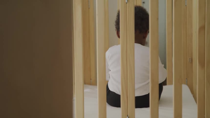 A child sitting down in a crib