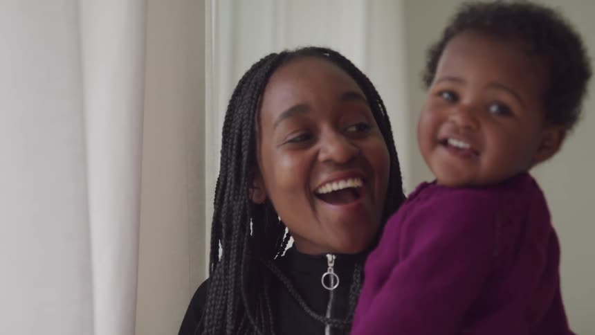 A mother holds her daughter and they smile
