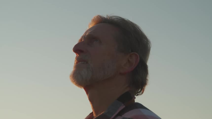 A man is standing outdoors at dusk