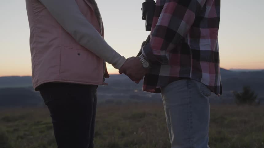 Couple holding hands in field at dawn