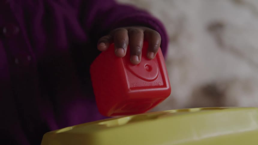 A young child plays with a red plastic block