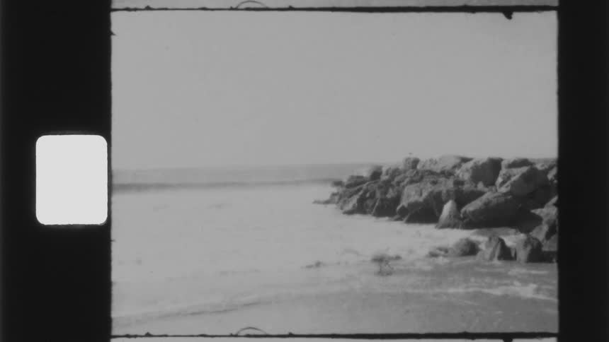 Ocean waves crash into a beach half covered in stone