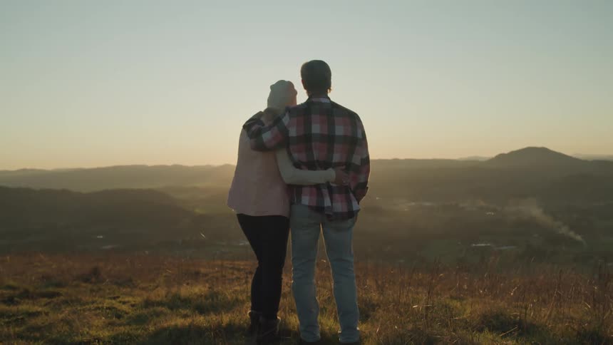 Man and woman are watching the sunset in the horizon together