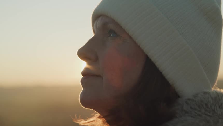 A woman watches the sunrise on a foggy day