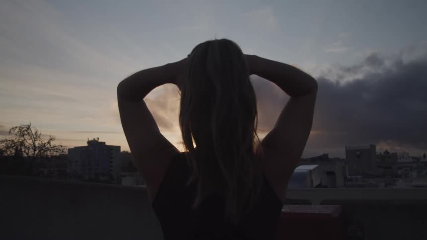 A woman is watching the sun set on the roof