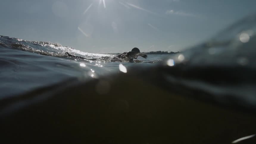 A man is paddling in the water on a surfboard