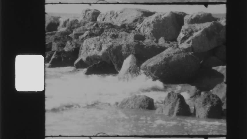 Ocean waves crash onto large rocks near the beach