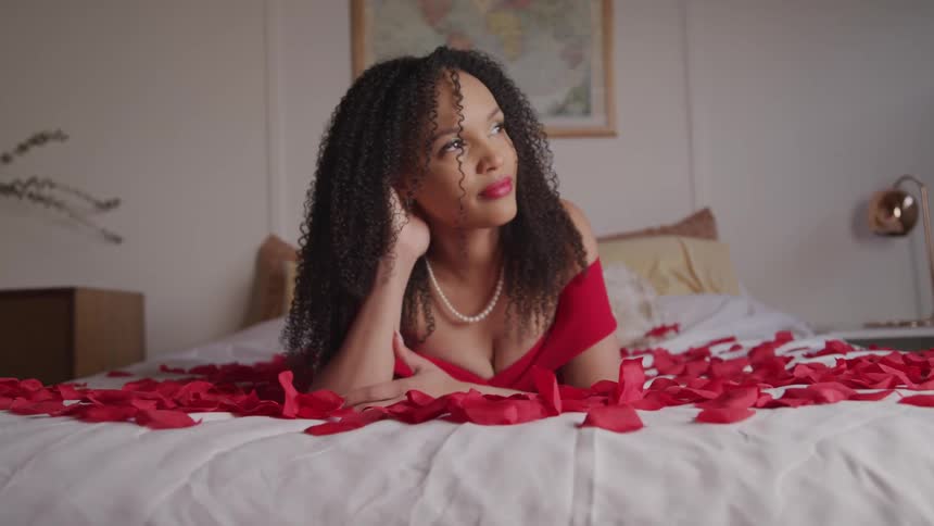 A woman all dressed up lying on a bed of flower petals