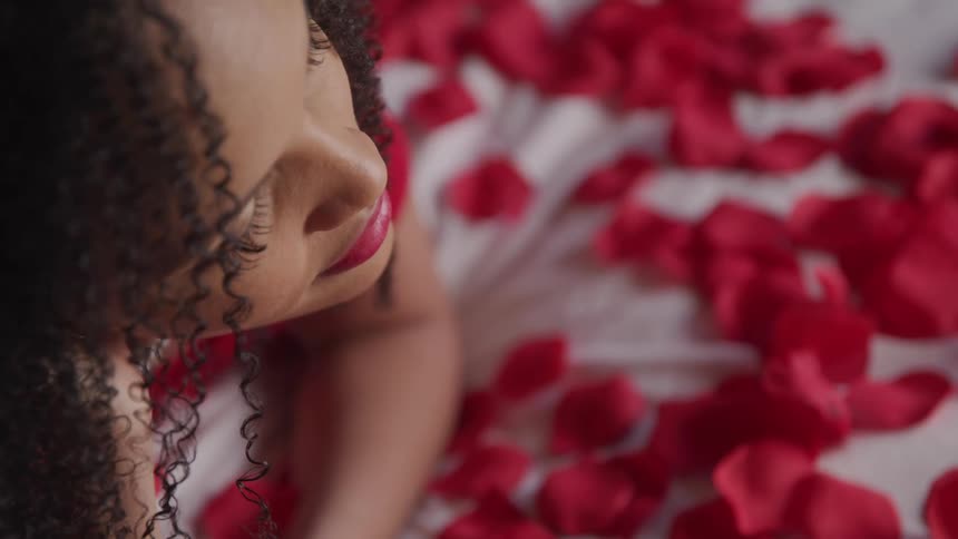 A woman is laying on a rose covered bed