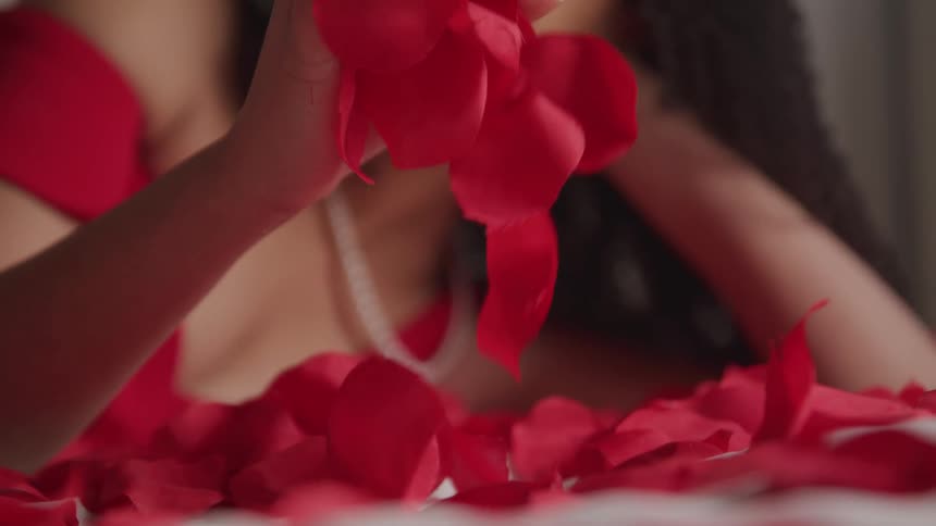 A female playing with rose petals while laying down