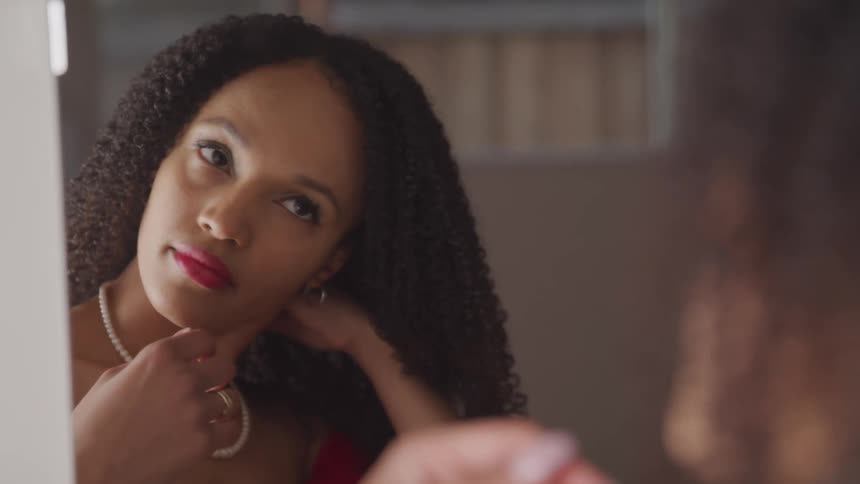 A woman at home looks in the mirror and fixes her hair