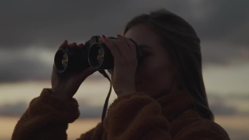 A woman is looking through a pair of binoculars