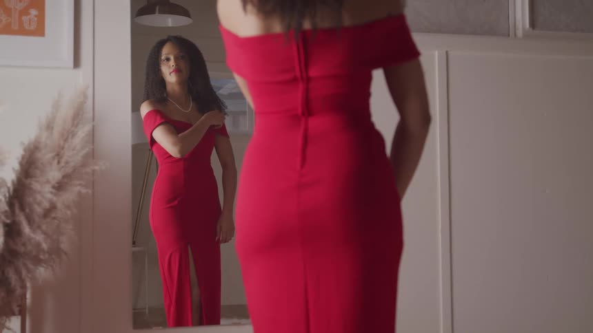 A woman is trying on a red dress