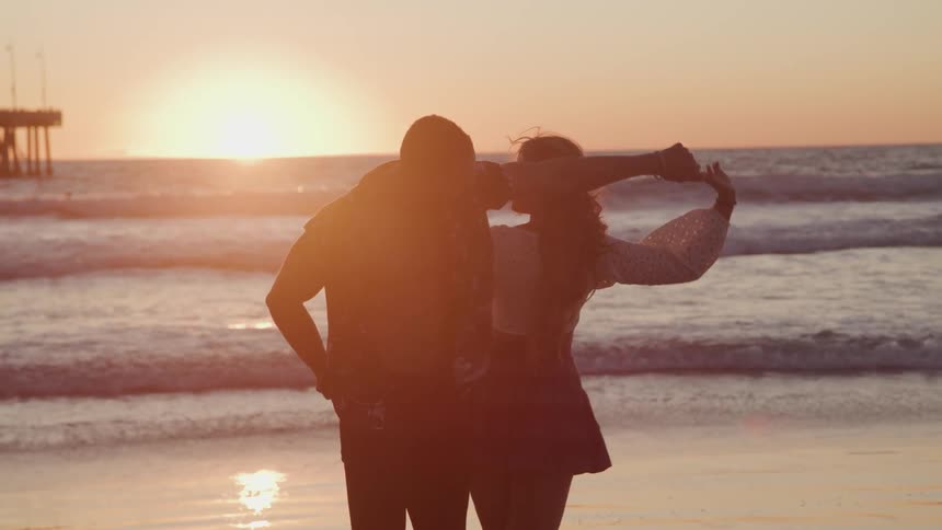 A man and woman dance together on the ocean beach