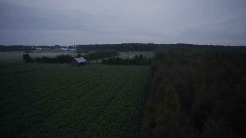 Fields lie between several wooded areas and a barn