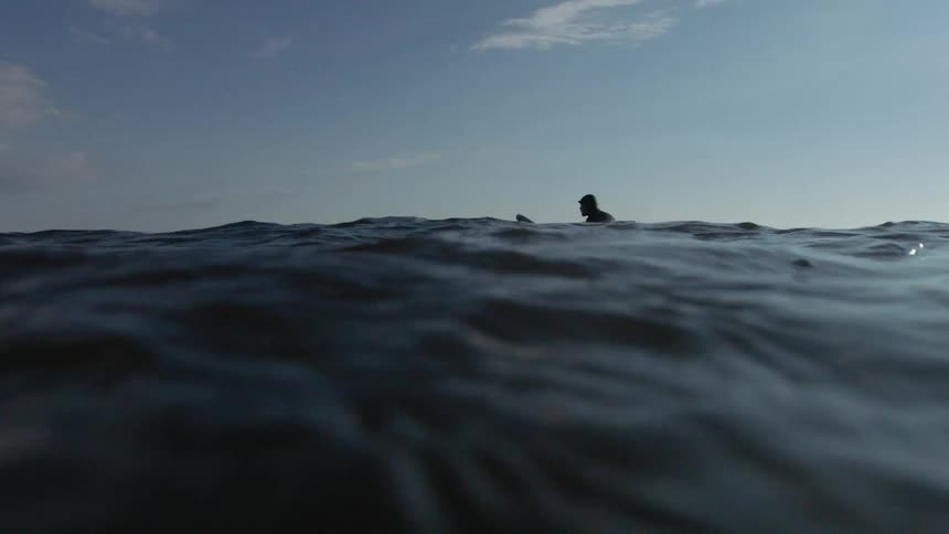 A man is floating in the water with his board