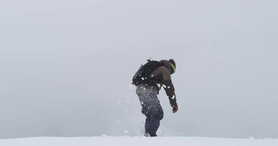A snowboarder jumps and takes off down the side of a mountain