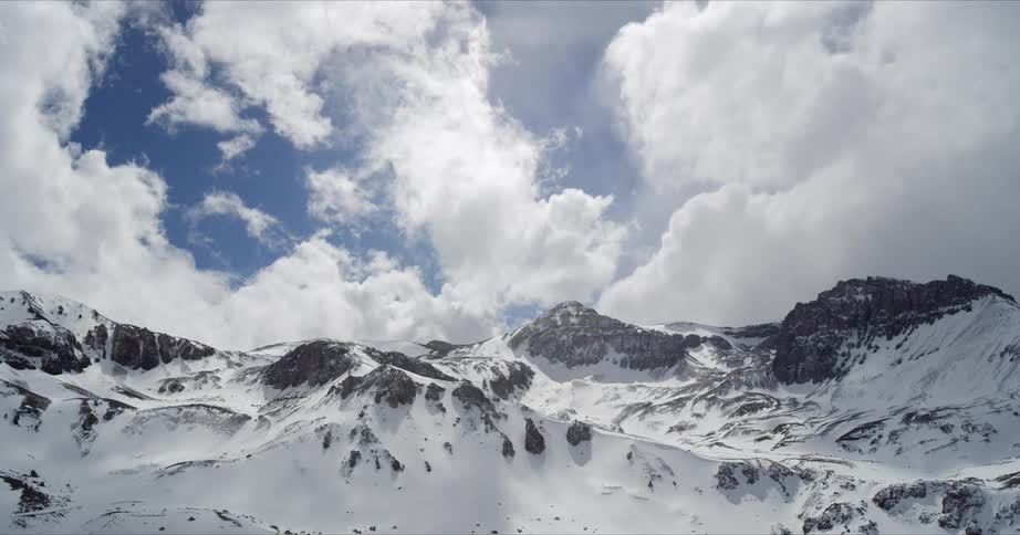 Timelapse of fluffy white clouds over a winter mountainscape