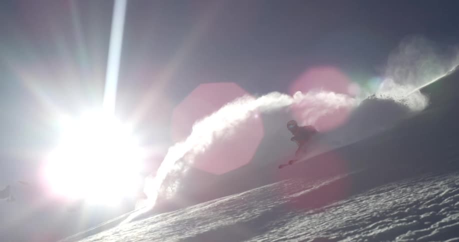 A skier gliding down a snowy mountainside on a sunny winter day