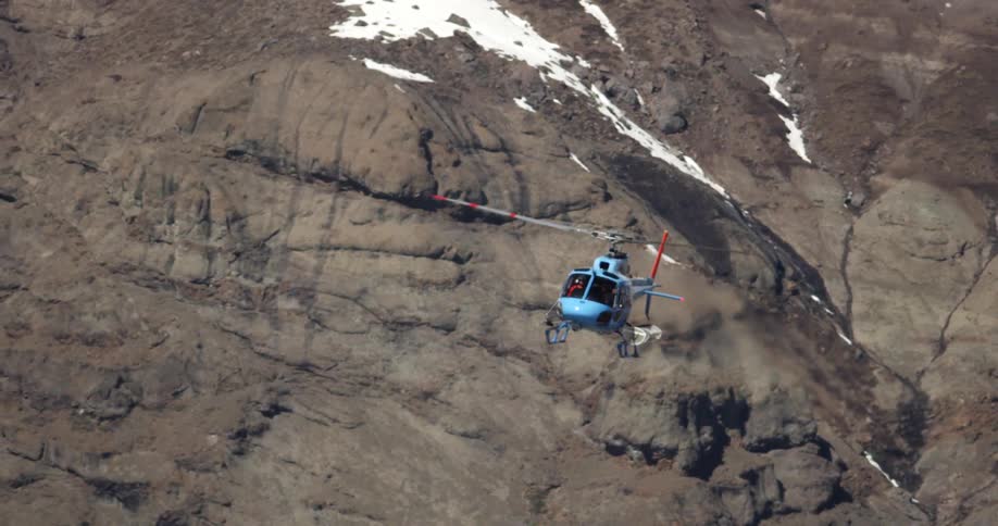 A helicopter is flying above the mountains