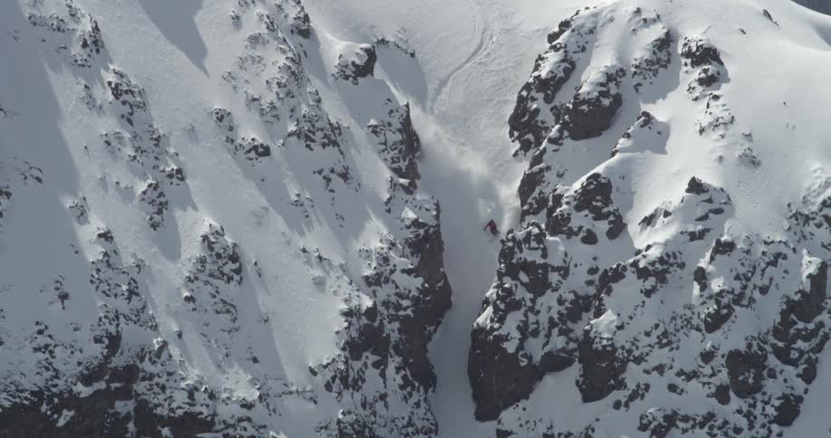 A skier flies through a narrow rock chute