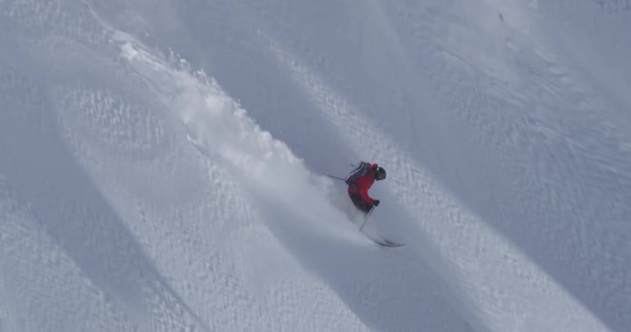 A skier makes turns down a steep slope